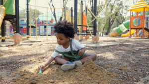 Preschool boy playing in sand on playground